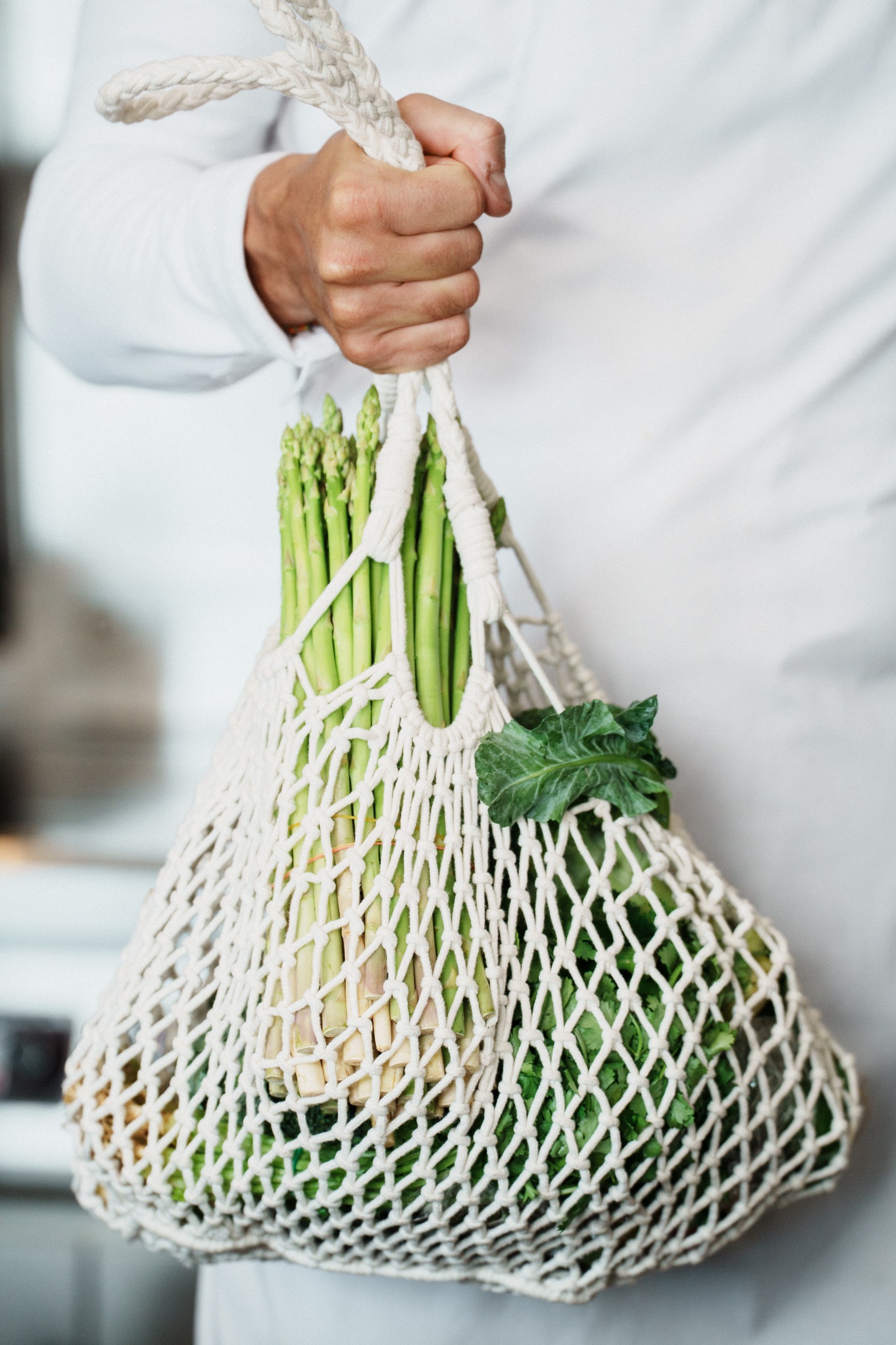 Chef holding asparagus in a net bag for restaurant social media channel strategy in Thailand