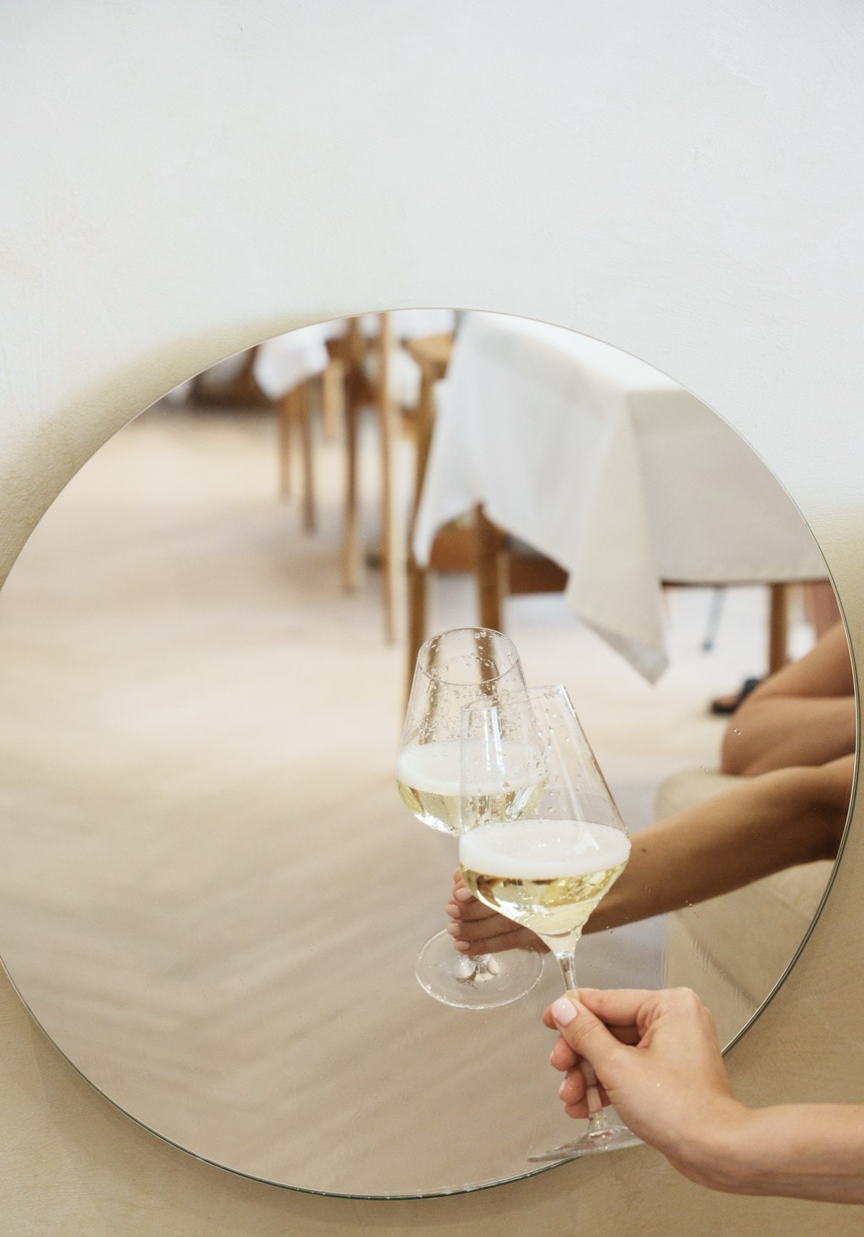 Wine glasses reflected in a round mirror inside a restaurant